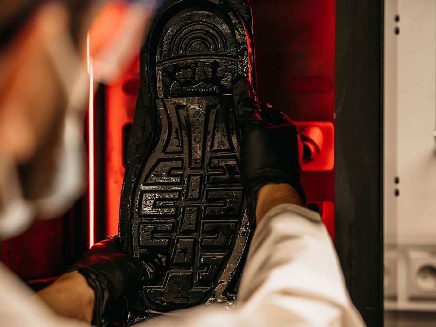 Man pulls shoe sole from Origin One printer.