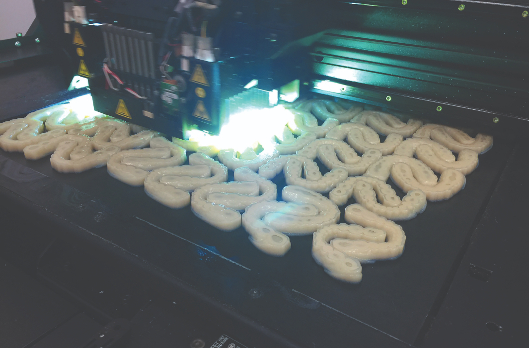 A myriad of dental implants are displayed on a build tray. 