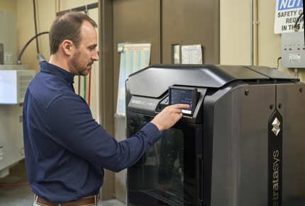Engineer standing next to a Stratasys printer.