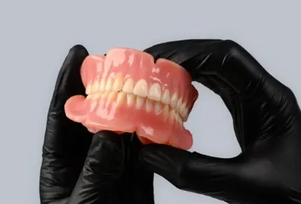 truedent-denture-held-by-gloved-hands