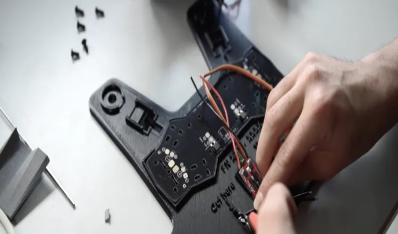A 3D printed PC-ESD fixture for PCB soldering. The board seats one way only, and wire cut points are marked directly on the fixture.
