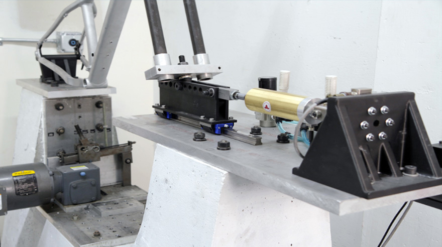 Black 3D printed carbon fiber-filled nylon 12 holding fixtures anchor a bike frame during fatigue testing.